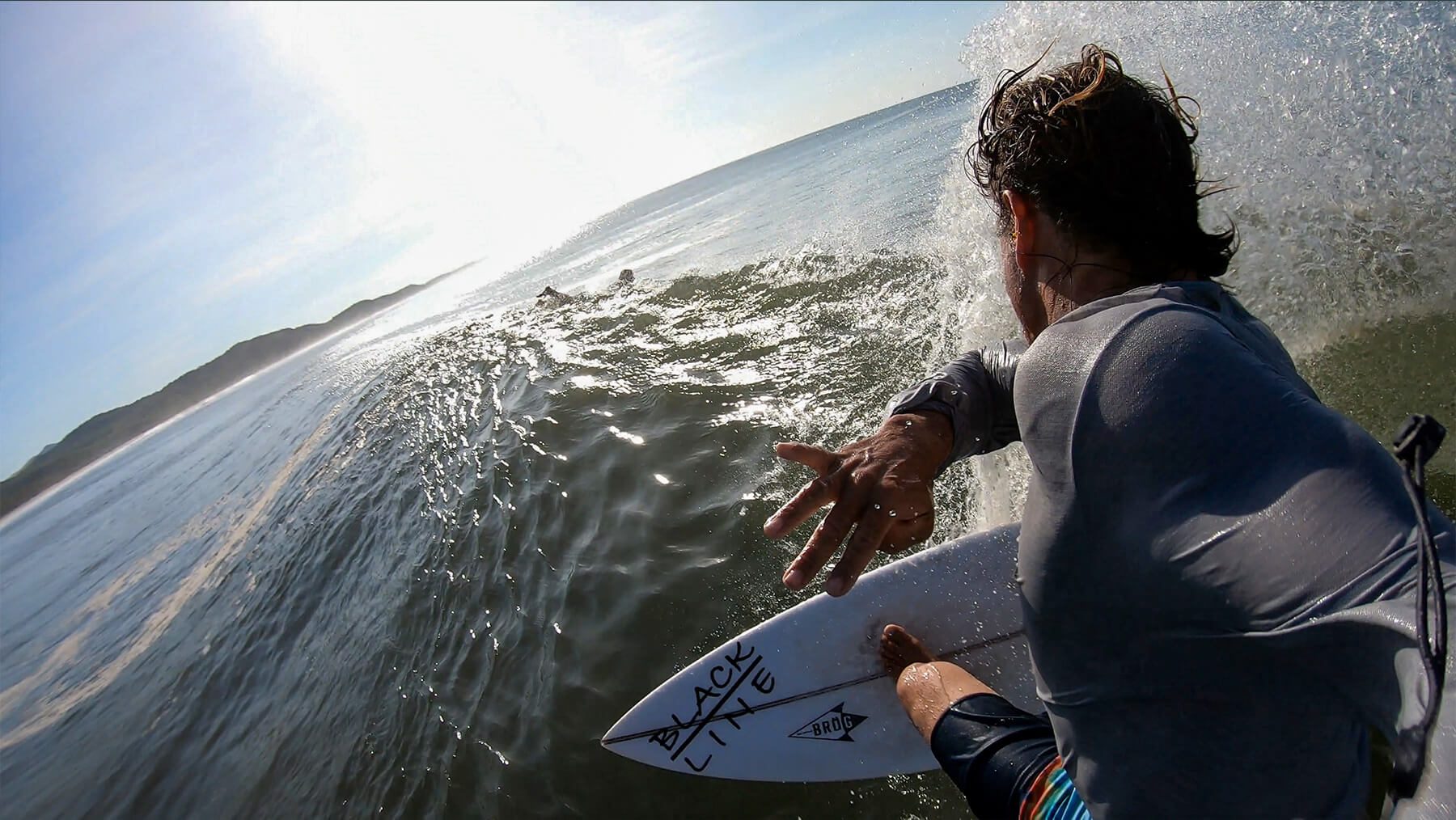 Surfer reaching out on a wave during a sunny day at the beach.